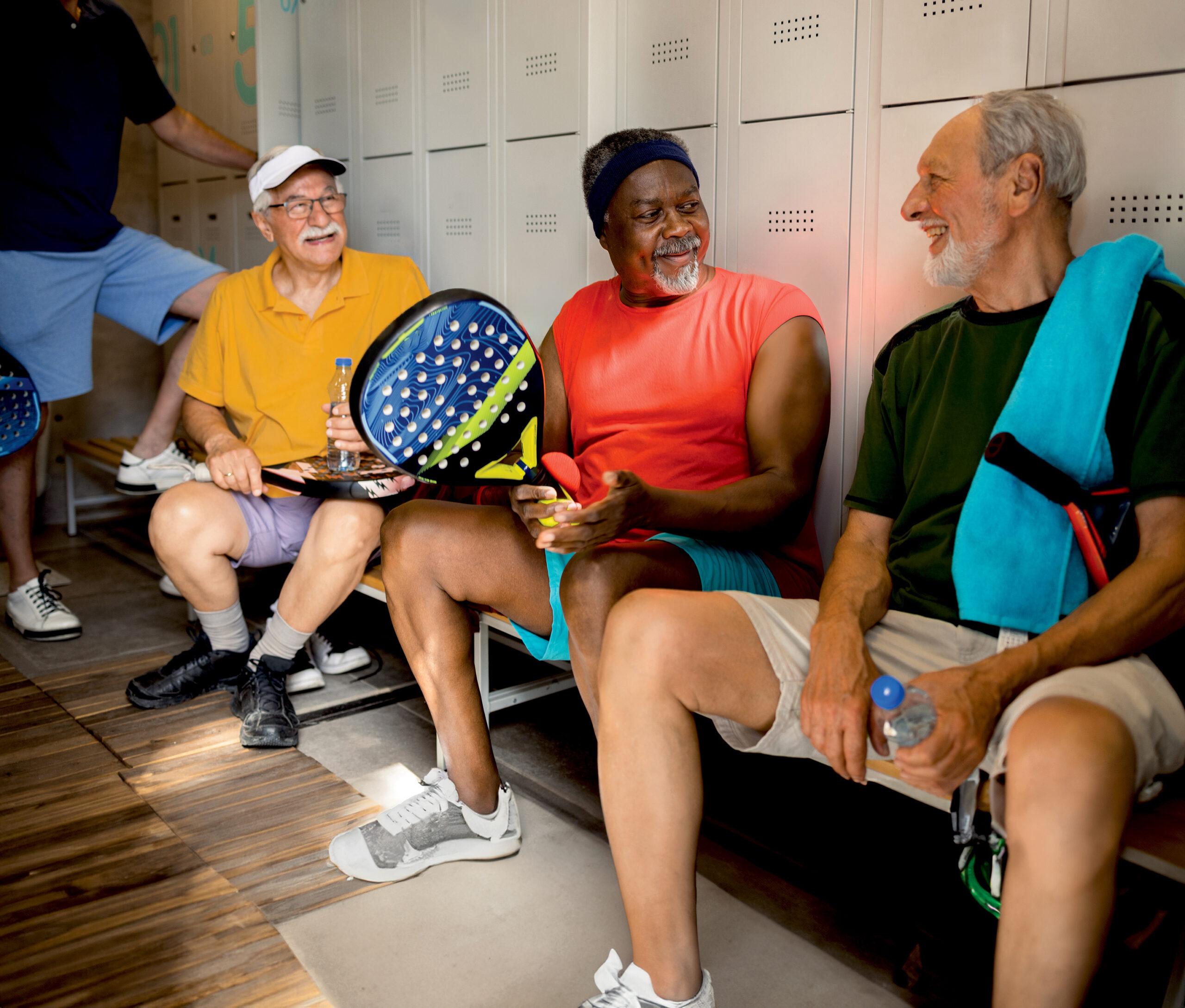 A group of friends talks and laughs in the locker room after a game of Paddle Tennis