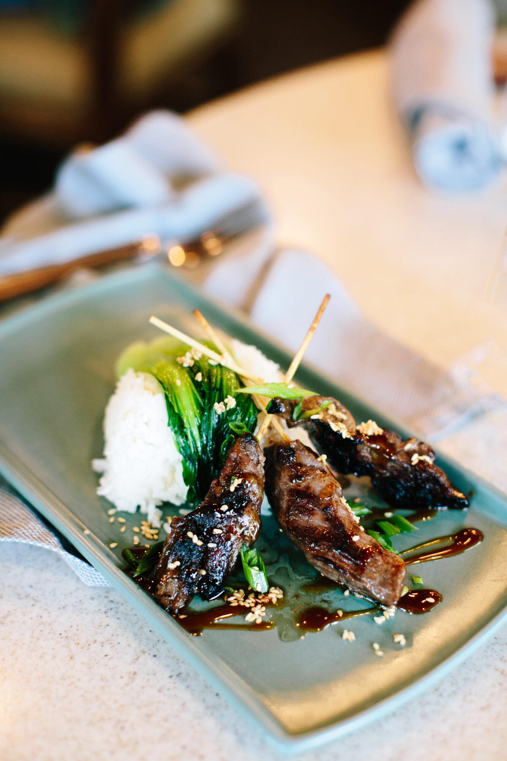 A gourmet plate of grilled meat, rice and greens