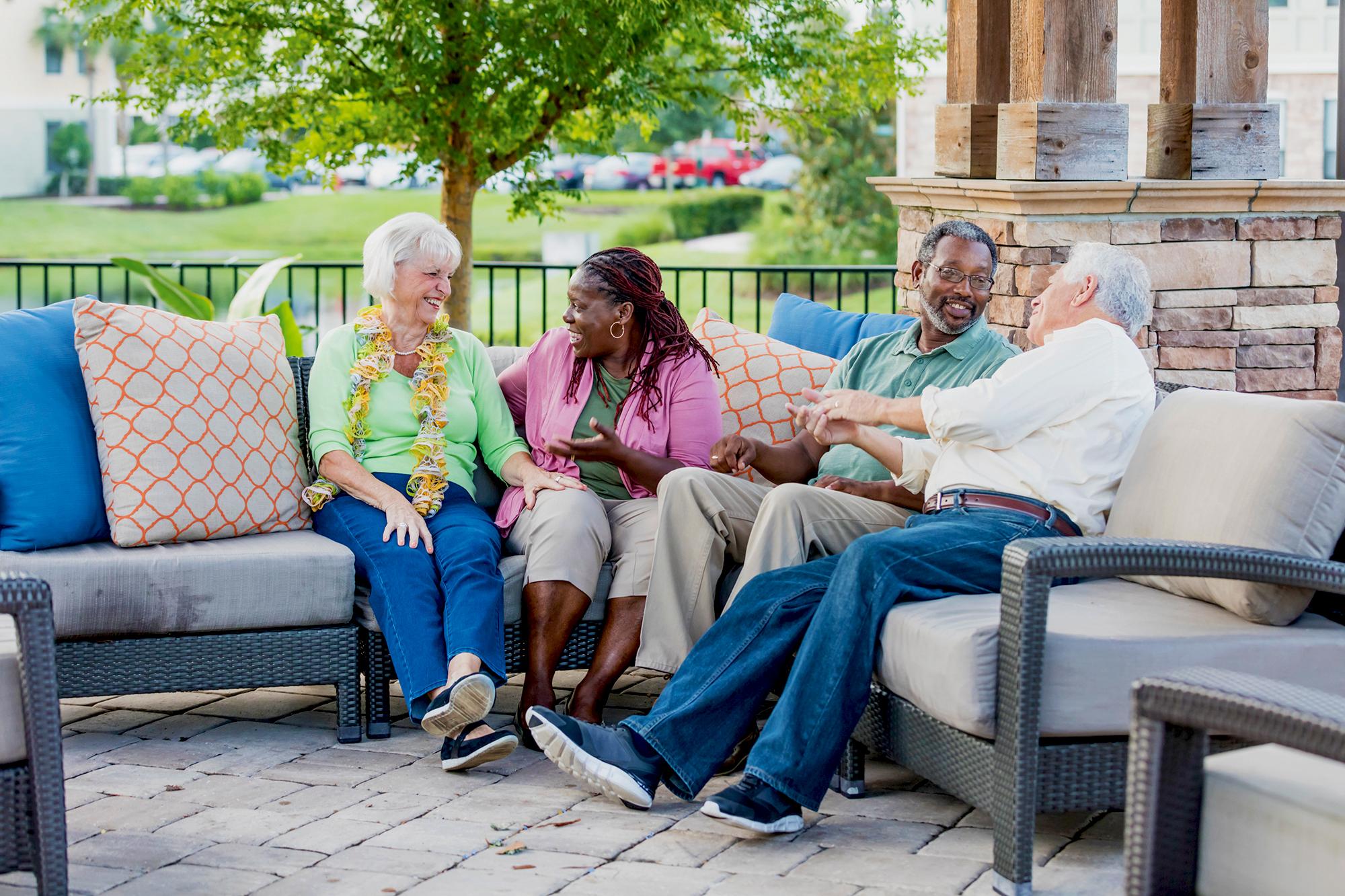 Two older couples hanging out on patio, conversing