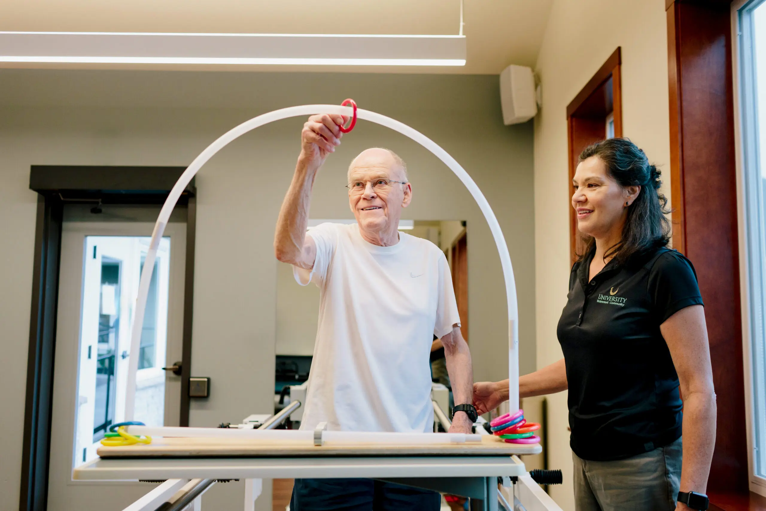 A nurse assists an older man with a physical therapy exercise